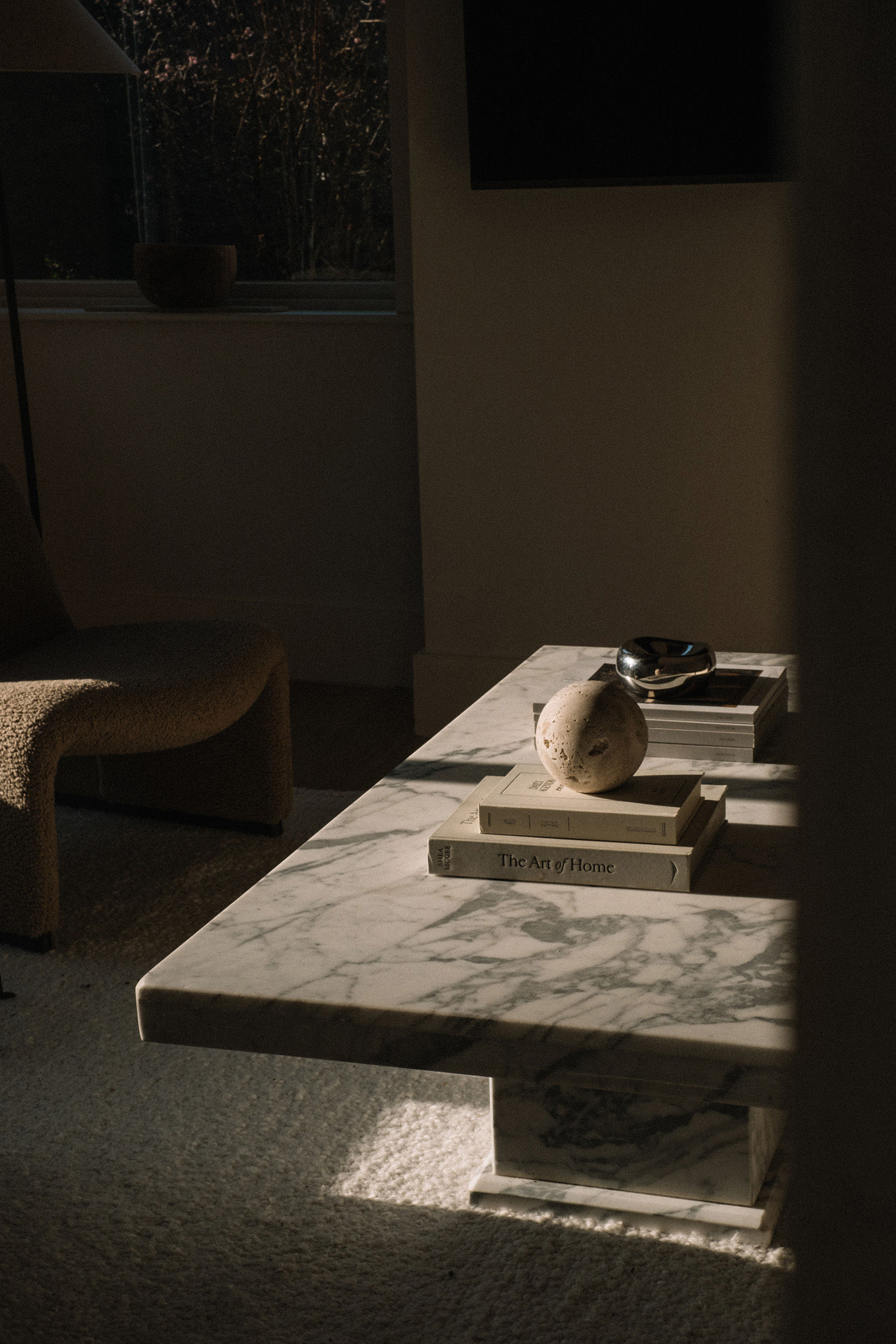 Marble coffee table styled with interiors books and a stone sphere
